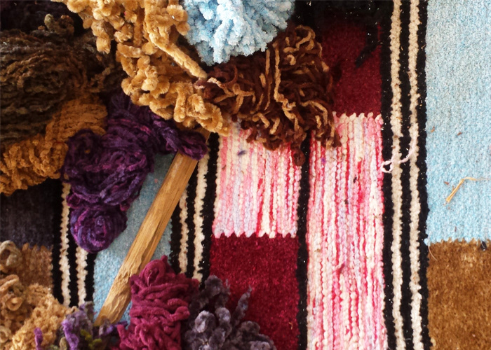 Colourful cotton yarn being woven into a striped rug