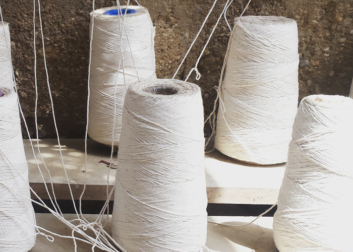 Large cones of white cotton thread prepared for rug production