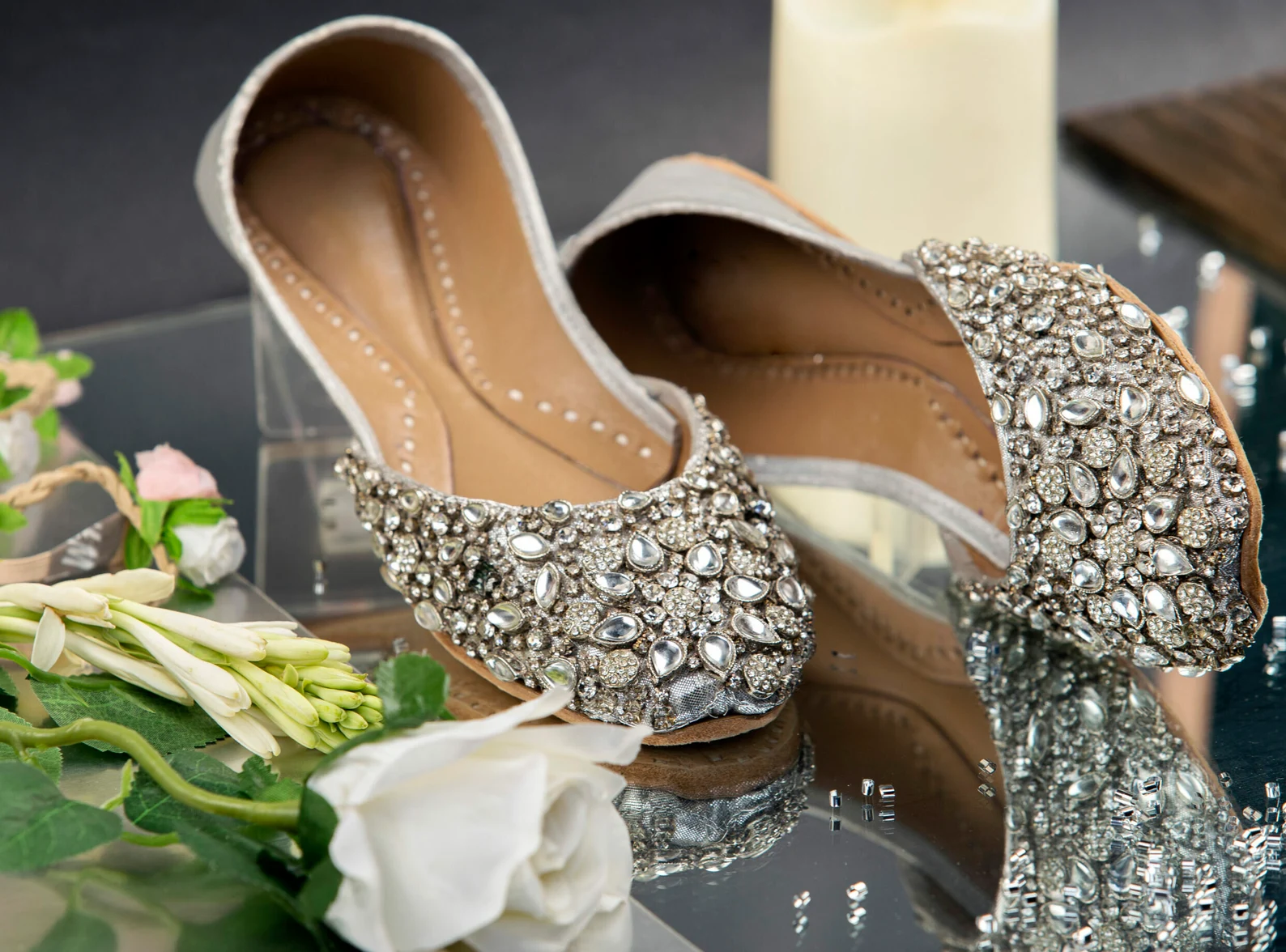 Silver mirror-work bridal juttis styled with white flowers