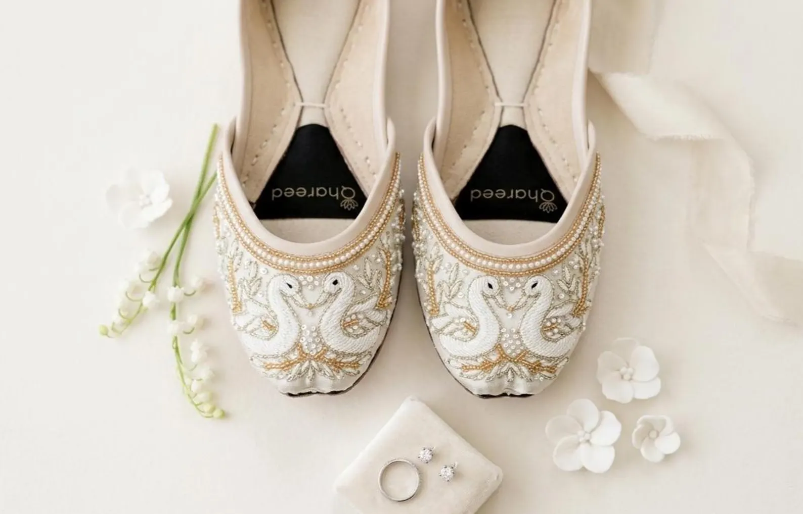 White swan-embroidered wedding juttis styled with bridal rings
